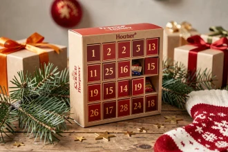 Calendrier de l'avent FDJ 2026 posé sur une table en bois décorée de branches de sapin et d'étoiles dorées